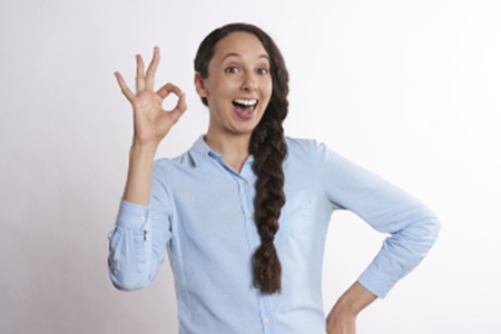 A woman with long hair is giving the ok sign.