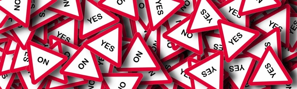 A pile of red and white triangle stickers with the word " no " on them.