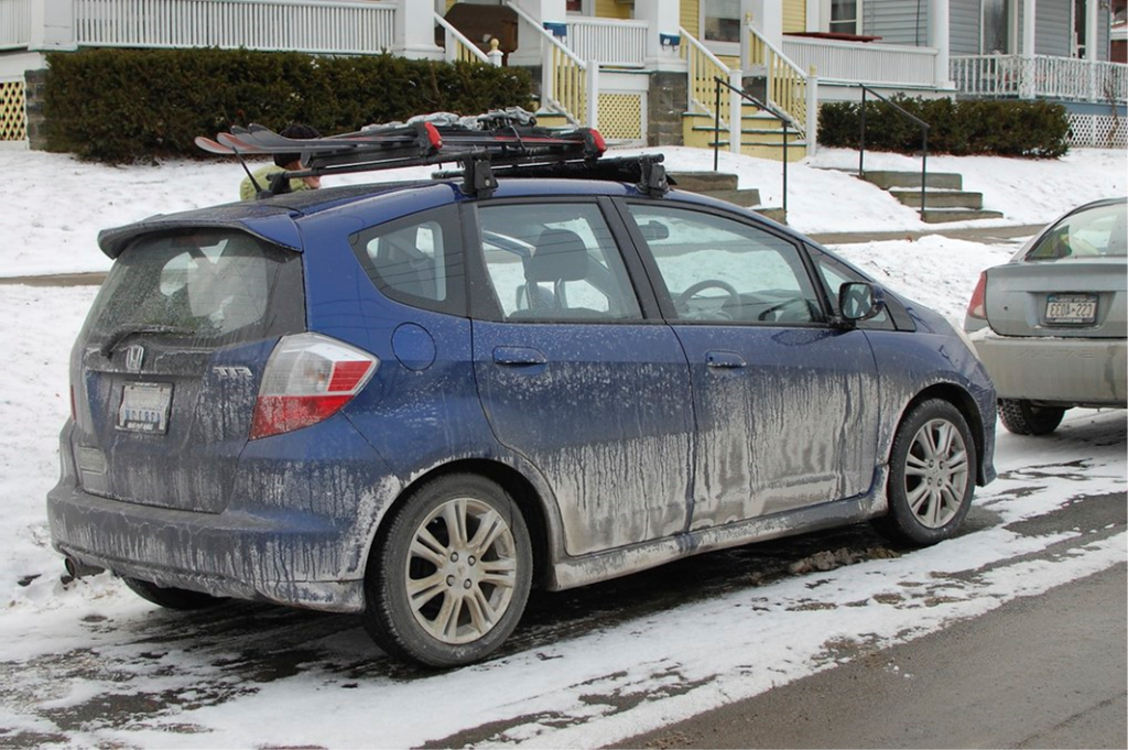 A blue car with snow on the top of it.