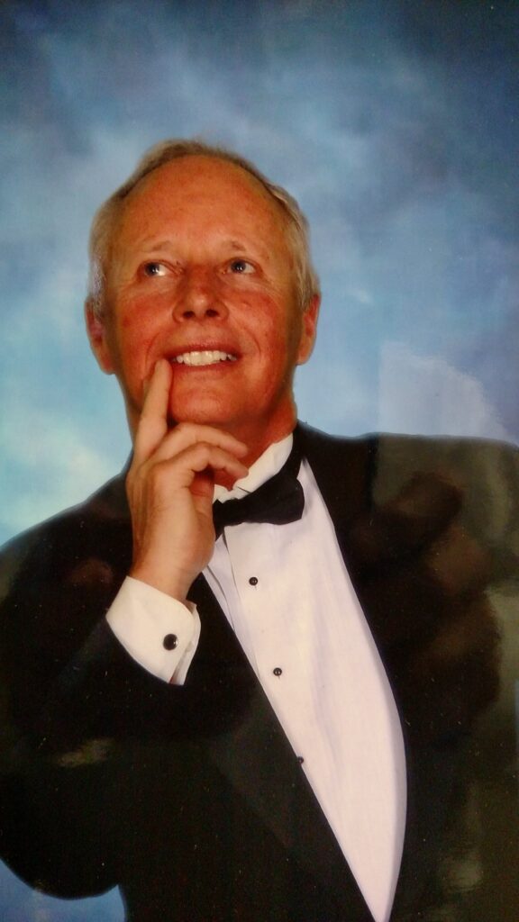 A man in a tuxedo and bow tie posing for the camera.