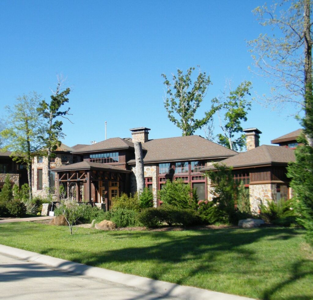 A large brown house with trees in the background